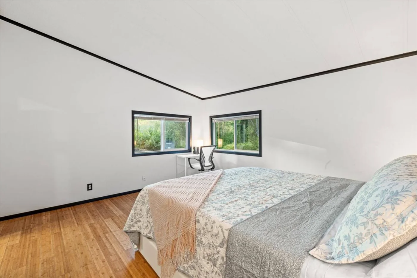 Habitación con cama y ventanas al bosque